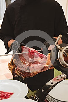 Professional ham carver cutting cured ham slices.