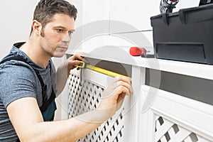 Professional handyman assembling radiator cabinet