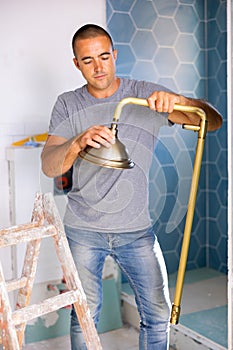 Professional handyman working in bathroom holding shower head indoors