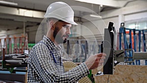 Professional heavy industry engineer worker wearing safety uniform and hard hat uses computer. Smiling industrial
