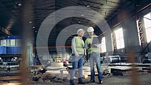 Professional heavy Industry Engineers. Two workers are talking in a building materials factory