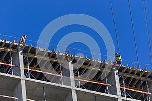 Professional high-rise installers buildings work on the top floor of a building under construction.