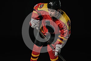 professional hockey player in protective sportswear holding hockey stick and looking away