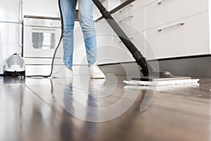 Professional home cleaning service. Woman washes the floor with a steam mop