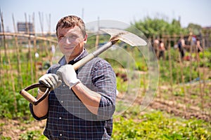 Professional horticulturist with garden shovel working at land