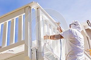 Professional House Painter Spray Painting A Deck of A Home