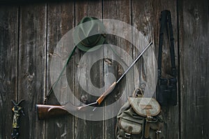 Professional hunters equipment for hunting. Rifle, hat, bag and others on a wooden black background.