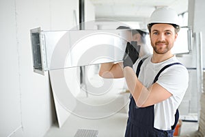 Professional HVAC Worker on a Aluminium Scaffolding Installing Air Duct Inside Newly Built Commercial Building