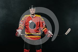 professional ice hockey player holding hockey stick and looking at camera