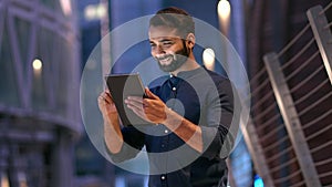 Professional indian business man using digital tablet outdoors in night city.