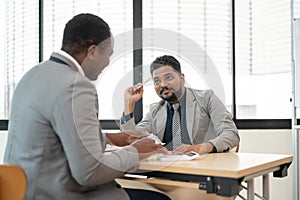 A professional Indian businessman is having a meeting with an African American real estate agent