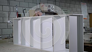 Professional industrial worker in a uniform assembling a furniture in workshop.
