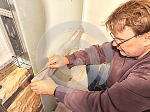 Professional Installs Drywall During Home Renovation. A skilled worker measures and secures drywall in home under