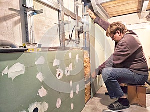 Professional Installs Drywall During Home Renovation. A skilled worker measures and secures drywall in home under