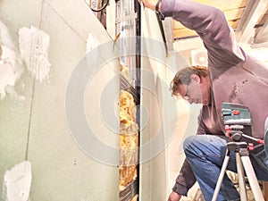 Professional Installs Drywall During Home Renovation. A skilled worker measures and secures drywall in home under