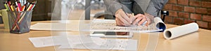 Professional Interior male designer working on blueprints on wood table at workspace. Architect Creative man hands drawing