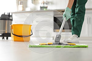 Professional janitor cleaning floor with mop in kitchen