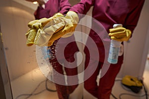 Professional janitor cleaning mirror in apartment hall