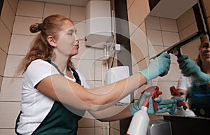 Professional janitor cleaning mirror with supplies photo