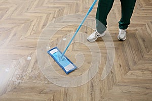 Professional janitor cleaning parquet floor with mop, closeup