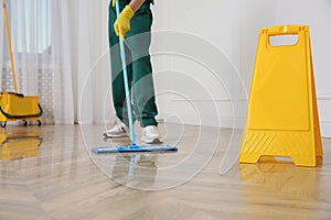 Professional janitor cleaning parquet floor with mop indoors, closeup