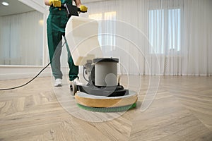 Professional janitor cleaning parquet floor with polishing machine indoors, closeup. Space for text