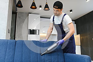 Professional janitor vacuuming armchair in room, closeup