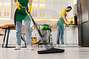 Professional janitor vacuuming floor in kitchen, closeup