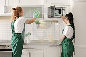 Professional janitors cleaning kitchen with supplies