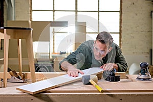 Professional joiner comparing, checking the length and surface of wooden material