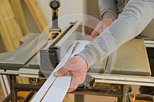 Professional joiner working with electric circular saw at woodworking for cutting wood filler strips