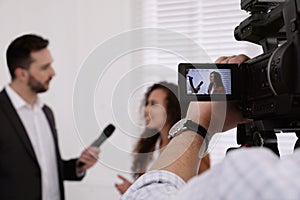 Professional journalist interviewing young African American woman and operator shooting video for broadcast