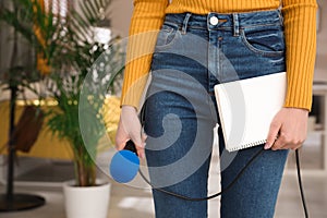 Professional journalist with modern microphone and notebook in room, closeup