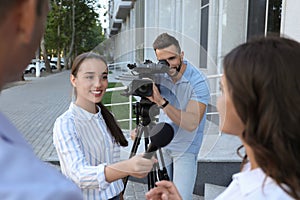 Professional journalist and operator with video camera taking interview outdoors photo