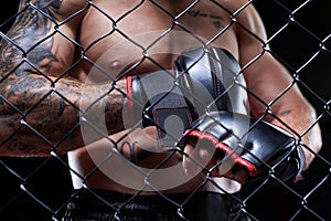 Professional kickboxing fighter puts on gloves in a cage ring. The concept of sports, Muay Thai, martial arts