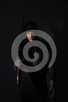 Professional killer with sniper rifle on black background