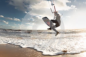 Professional kite surfer jump on sunset beach