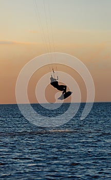 Professional kiter doing a complicated trick on a beautiful sunset background