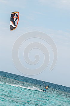 Professional kiter glide the water surface of the ocean at great speed. Back view behind extreme wide shot