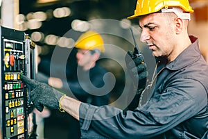 Professional labor worker engineer monitor at machine control panel and radio talking communication with coworker during press the