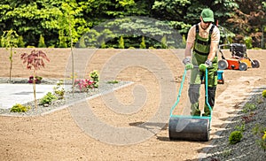 Professional Landscaper Preparing Backyard Garden Soil For Grass Seeding