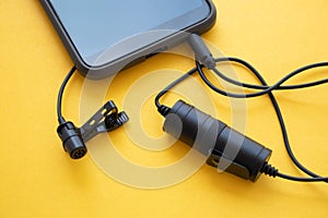 Professional lavalier or lapel microphone on a colored surface. close-up . The details of the grip clip or bra, powerbank and