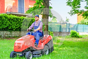 Professional lawn mower worker cutting grass in home garden