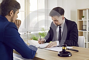 Professional lawyer or attorney signing some documents during a meeting with his client