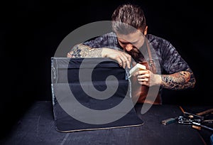 Professional Leather Worker performing leatherwork on a new product piece at the desk