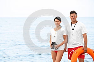 Professional lifeguards with life buoy and binocular at beach