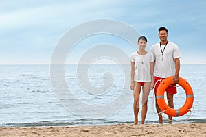 Professional lifeguards with life buoy at sandy beach