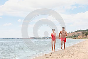 Professional lifeguards running at sandy beach on sunny day