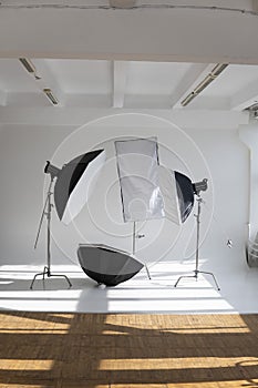 Professional lighting equipment, flashes, c-stands on a cyclorama in modern photo studio with a huge windows. Octabox