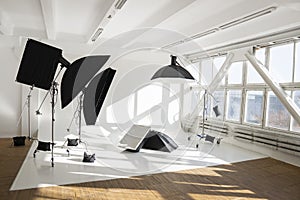 Professional lighting equipment, flashes, c-stands on a cyclorama in modern photo studio with a huge windows. Octabox